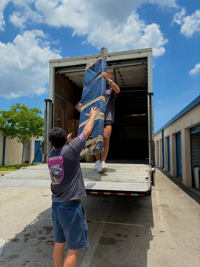 Crew lifting a blanket-wrapped piece into the truck